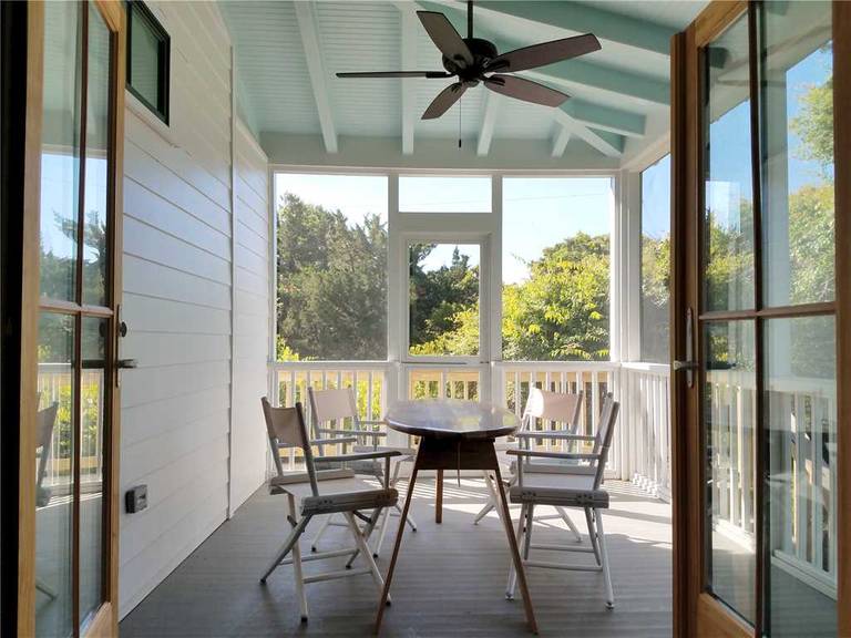 Looking through french doors as the Front Porch with Fan, table and chairs